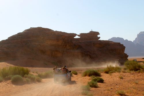 A group of students ride a truck through a desert in Jordan.
